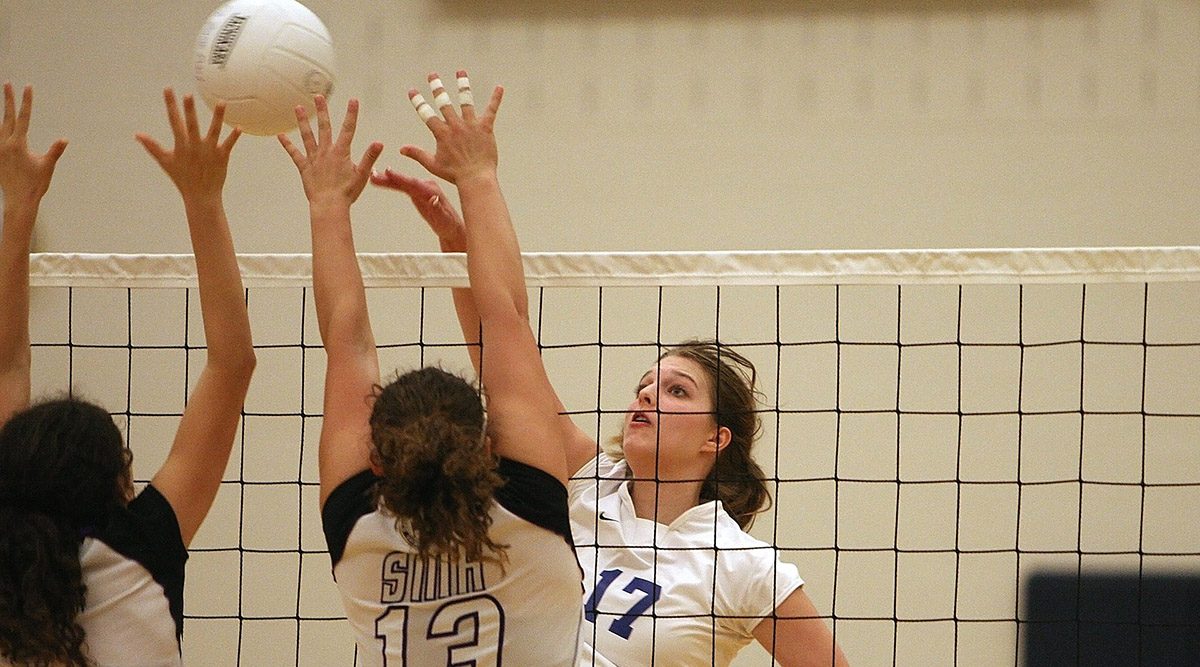 A girl attacking the ball with two blockers up