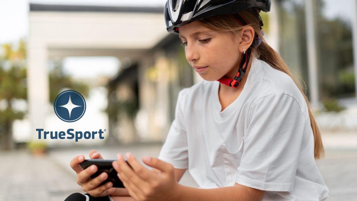 A young girl with a bike helmet on looks at her phone